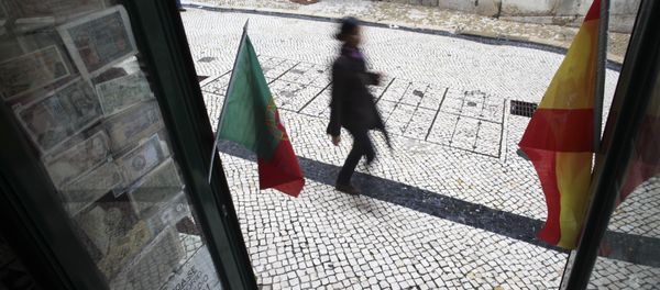 A woman walks past a coin collectors' shop with the flags of Spain and Portugal (File) A woman walks past a coin collectors' shop with the flags of Spain and Portugal (File) - Sputnik International