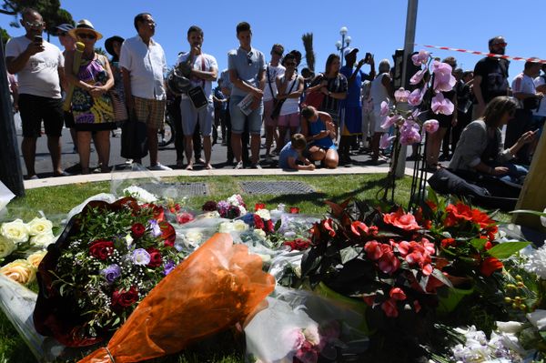People stand on July 15, 2016 in front of flowers and candles placed near the site in Nice where a gunman smashed a truck into a crowd of revellers celebrating Bastille Day, killing at least 84 people. - Sputnik International