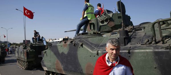 A man wrapped in a Turkish flag stands next to military vehicles in front of Sabiha Airport, in Istanbul, Turkey July 16, 2016. - Sputnik International