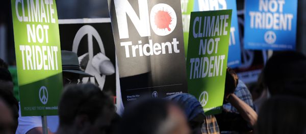 Demonstrators hold placards calling for government funds to be spent on the NHS and climate change, as they attend an anti-war and anti-trident demonstration near the Houses of Parliament in central London on July 18, 2016 Demonstrators hold placards calling for government funds to be spent on the NHS and climate change, as they attend an anti-war and anti-trident demonstration near the Houses of Parliament in central London on July 18, 2016 - Sputnik International