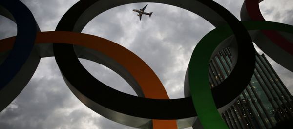 An airplane flies past Olympic rings placed at the entrance of office building ahead of the Rio 2016 Olympic Games, in Sao Paulo, Brazil, July 19, 2016 - Sputnik International