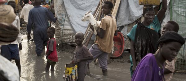 South-Sudanese man carries a goat as he and others wade through mud-filled paths between makeshift tents in the United Nations base (File) - Sputnik International