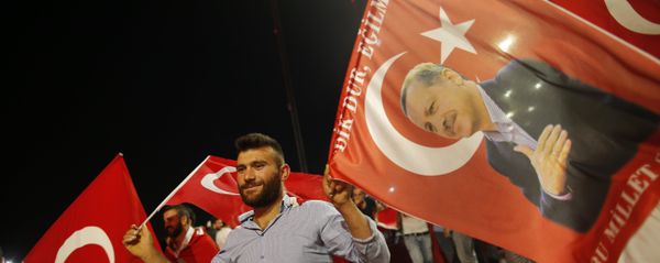 A pro-government supporter waves a Turkish flag and one with the picture of Turkey's President Recep Tayyip Erdogan, right, during a rally on the road leading to Istanbul's iconic Bosporus Bridge, Thursday, July 21, 2016 - Sputnik International