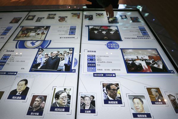 A visitor, top, looks at an electronic screen displaying images and convicted corruption charges of China's fallen politicians, Bo Xilai, bottom second right, Zhou Yongkang, bottom left, and other senior officials, at the China Court Museum in Beijing, Tuesday, Jan. 12, 2016 - Sputnik International