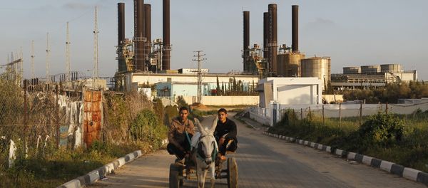 Palestinians ride a donkey-pulled cart past Gaza's sole power plant in Nusairat - Sputnik International