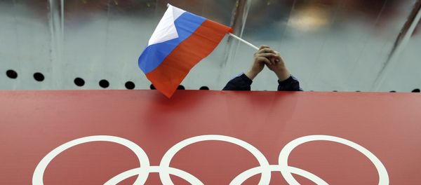 Russian skating fan holds the country's national flag over the Olympic rings before the start of the men's 10,000-meter speedskating race at Adler Arena Skating Center during the 2014 Winter Olympics in Sochi, Russia. (File) - Sputnik International