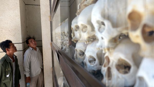 Cambodian men looks at skulls of victims killed by the Khmer Rouge regime at the Choeung Ek killing fields memorial - Sputnik International
