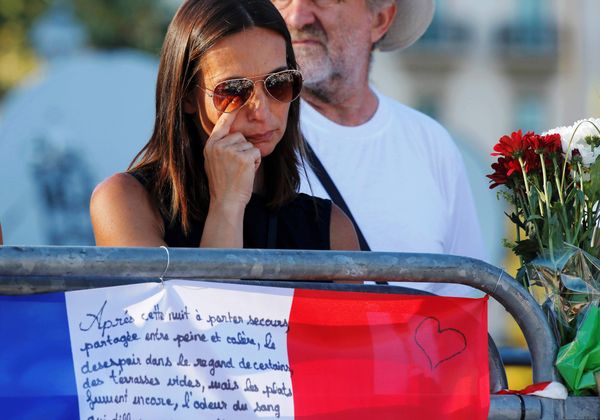 A woman reacts near flowers and flags placed in tribute to victims, two days after an attack by the driver of a heavy truck who ran into a crowd on Bastille Day killing scores and injuring as many on the Promenade des Anglais, in Nice, France, July 16, 2016. - Sputnik International