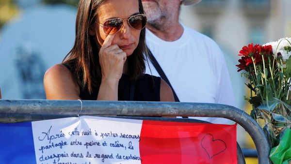 A woman reacts near flowers and flags placed in tribute to victims, two days after an attack by the driver of a heavy truck who ran into a crowd on Bastille Day killing scores and injuring as many on the Promenade des Anglais, in Nice, France, July 16, 2016. A woman reacts near flowers and flags placed in tribute to victims, two days after an attack by the driver of a heavy truck who ran into a crowd on Bastille Day killing scores and injuring as many on the Promenade des Anglais, in Nice, France, July 16, 2016. - Sputnik International