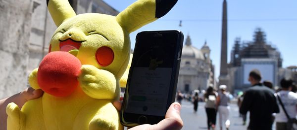 A gamer holds a Pokemon mascot and his mobile phone as he plays with the Pokemon Go application in central Rome on July 19, 2016 - Sputnik International