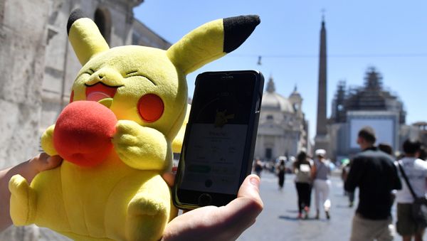 A gamer holds a Pokemon mascot and his mobile phone as he plays with the Pokemon Go application in central Rome on July 19, 2016 A gamer holds a Pokemon mascot and his mobile phone as he plays with the Pokemon Go application in central Rome on July 19, 2016 - Sputnik International
