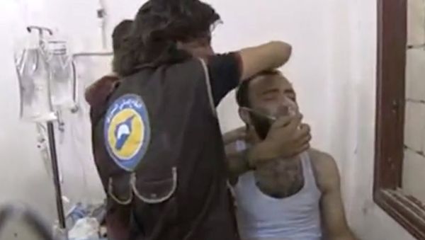 Two men standing over a man on a bed, making him sit up as he breathes through a mask in what is said to be in Saraqeb, Idlib province, Syria - Sputnik International