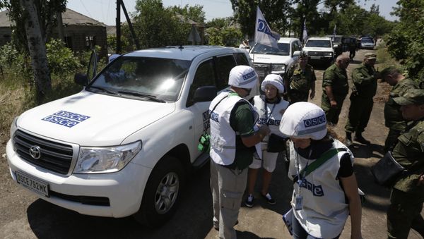 Members of the Organization for Security and Co-operation in Europe (OSCE) stand in the village of Shyrokyne, Donetsk region on July 4, 2015 - Sputnik International