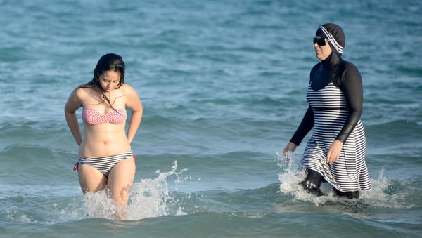 Tunisian women, one (R) wearing a burkini, a full-body swimsuit designed for Muslim women, swim on August 16, 2016 at Ghar El Melh beach near Bizerte, north-east of the capital Tunis. Tunisian women, one (R) wearing a burkini, a full-body swimsuit designed for Muslim women, swim on August 16, 2016 at Ghar El Melh beach near Bizerte, north-east of the capital Tunis. - Sputnik International