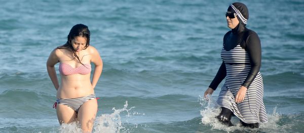 Tunisian women, one (R) wearing a burkini, a full-body swimsuit designed for Muslim women, swim on August 16, 2016 at Ghar El Melh beach near Bizerte, north-east of the capital Tunis. Tunisian women, one (R) wearing a burkini, a full-body swimsuit designed for Muslim women, swim on August 16, 2016 at Ghar El Melh beach near Bizerte, north-east of the capital Tunis. - Sputnik International