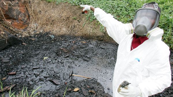 A civil protection member of Ivory Coast points at a site polluted with toxic waste at the Akouedo district in Abidjan 19 September 2006. In mid-August the Probo Koala ship unloaded in Abidjan more than 500 tonnes of a highly toxic mixture of oil residue and caustic soda used to rinse out the ship's tanks. The poisons are known to cause nausea, rashes, fainting, diarrhoea and headaches. Besides the seven deaths, 24 people are still hospitalized and more than 37,000 have sought medical treatment. - Sputnik International