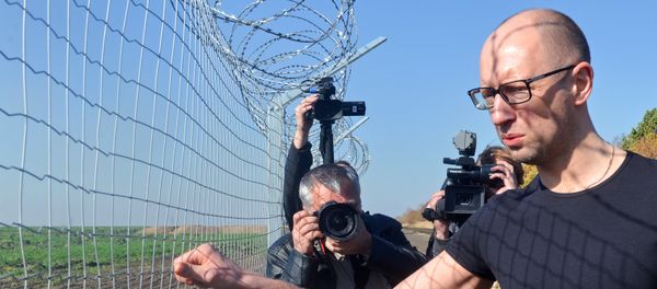 Ukrainain Prime Minister Arseniy Yatsenyuk (R) touches a piece of gate as he visits a newly constructed section of the Ukrainian-Russian border, near the Goptivka border crossing, north of Kharkiv, eastern Ukraine, on October 15, 2014 - Sputnik International
