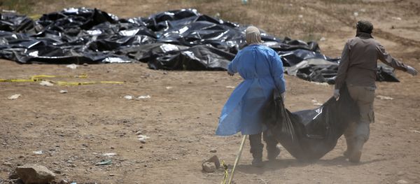 Members of the Iraqi security forces work at the site of a mass grave containing the remains of people believed to have been slain by jihadists of the Islamic State (IS) group at the Speicher camp in the city of Tikrit, on April 12, 2015 - Sputnik International