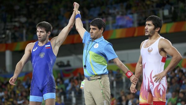 2016 Rio Olympics - Wrestling - Semifinal - Men's Freestyle 65 kg Semifinal - Carioca Arena 2 - Rio de Janeiro, Brazil - 21/08/2016. The referee raises the hand of Soslan Ramonov (RUS) of Russia after his victory against Ikhtiyor Navruzov (UZB) of Uzbekistan - Sputnik International