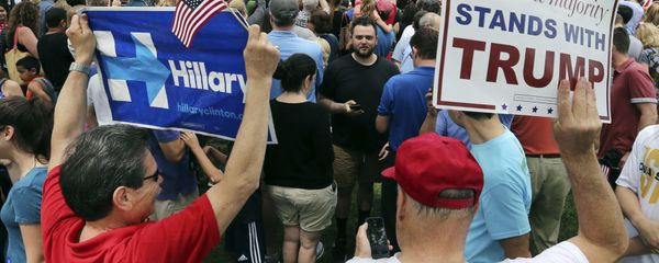 A supporter of Democratic presidential candidate Hillary Clinton and a Republican presidential candidate Donald Trump supporter hold signs as they attend a Memorial Day parade Monday, May 30, 2016, in Chappaqua, N.Y. Clinton and her husband former President Bill Clinton, along with New York Gov. Andrew Cuomo, walked in the parade - Sputnik International
