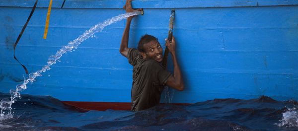 A man holds himself on the side of a boat after jumping into the sea from a crowded wooden boat during a rescue operation at the Mediterranean sea, about 13 miles north of Sabratha, Libya, Monday, Aug. 29, 2016. A man holds himself on the side of a boat after jumping into the sea from a crowded wooden boat during a rescue operation at the Mediterranean sea, about 13 miles north of Sabratha, Libya, Monday, Aug. 29, 2016. - Sputnik International