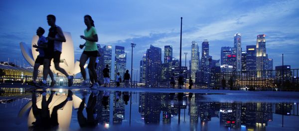 Joggers run past as the skyline of Singapore's financial district is seen in the background Joggers run past as the skyline of Singapore's financial district is seen in the background - Sputnik International