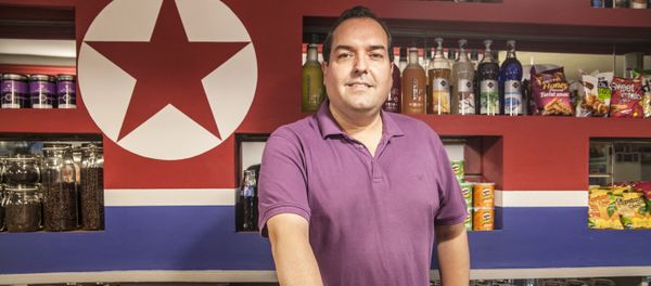 Alejandro Cao de Benós poses in Café Pyongyang with North Koeran flag on the background - Sputnik International