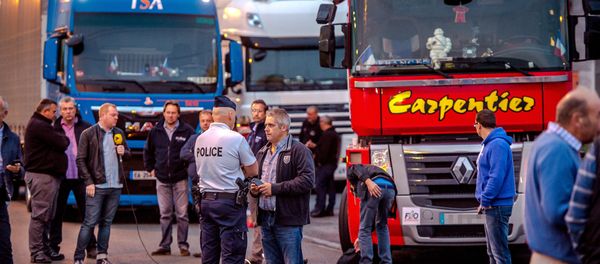 A man speaks with a police officer as a dozen of truck drivers gather in a parking on September 5, 2016 in Loon Plage prior to a slow-down operation on the A16 highway to ask for the dismantling of the so-called Jungle migrant camp in the French northern port city of Calais - Sputnik International