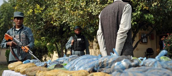 An Afghan policeman (L) stands guard as a detained suspect and bags containing heroin are presented to the media at a police station in Jalalabad on November 17, 2012. An Afghan policeman (L) stands guard as a detained suspect and bags containing heroin are presented to the media at a police station in Jalalabad on November 17, 2012. - Sputnik International
