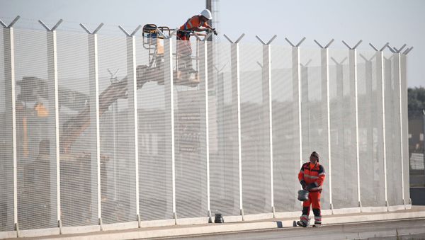 Workers set-up barbed wires on top of a fence along the harbour of Calais to prevent migrants jumping aboard lorries, France, September 7, 2016 - Sputnik International