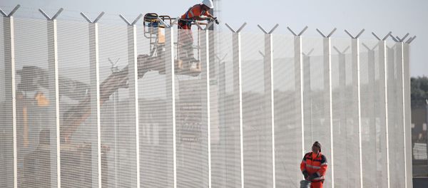 Workers set-up barbed wires on top of a fence along the harbour of Calais to prevent migrants jumping aboard lorries, France, September 7, 2016 Workers set-up barbed wires on top of a fence along the harbour of Calais to prevent migrants jumping aboard lorries, France, September 7, 2016 - Sputnik International