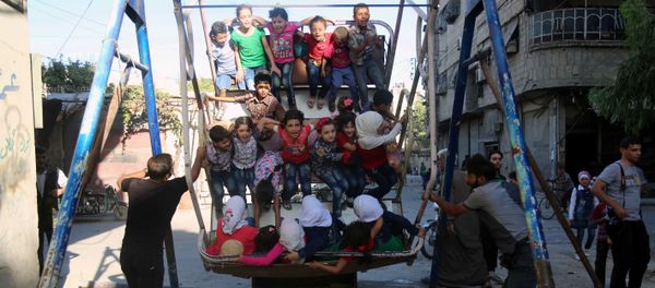 Syrian children ride an attraction in the Syrian rebel-held town of Arbin, in the eastern Ghouta region on the outskirts of the capital Damascus, as they celebrate the Muslim Eid al-Adha holiday on September 13, 2016 - Sputnik International