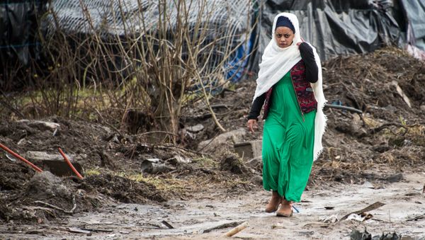 A migrant woman walks along a muddy path in the so-called Jungle refugee and migrant camp in Calais, on February 24, 2016. - Sputnik International