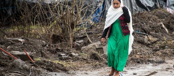 A migrant woman walks along a muddy path in the so-called Jungle refugee and migrant camp in Calais, on February 24, 2016. A migrant woman walks along a muddy path in the so-called Jungle refugee and migrant camp in Calais, on February 24, 2016. - Sputnik International