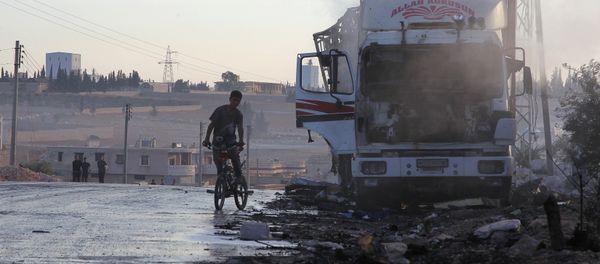 A boy rides a bicycle near a damaged aid truck after an airstrike on the rebel held Urm al-Kubra town, western Aleppo city, Syria September 20, 2016. - Sputnik International