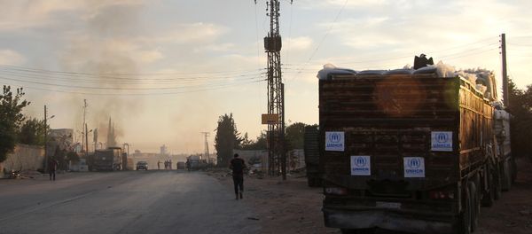 Smoke rises in the distance as Syrians gather near damaged trucks carrying aid on the side of the road in the town of Orum al-Kubra on the western outskirts of the northern Syrian city of Aleppo on September 20, 2016, the morning after a convoy delivering aid was hit by a deadly air strike Smoke rises in the distance as Syrians gather near damaged trucks carrying aid on the side of the road in the town of Orum al-Kubra on the western outskirts of the northern Syrian city of Aleppo on September 20, 2016, the morning after a convoy delivering aid was hit by a deadly air strike - Sputnik International