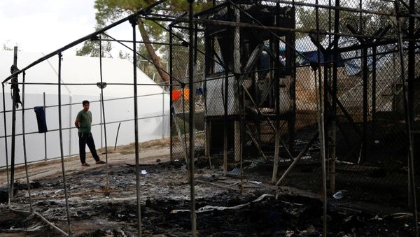 A migrant stands next to a burned tent at the Moria migrant camp, after a fire that ripped through tents and destroyed containers during violence among residents, on the island of Lesbos, Greece, September 20, 2016. A migrant stands next to a burned tent at the Moria migrant camp, after a fire that ripped through tents and destroyed containers during violence among residents, on the island of Lesbos, Greece, September 20, 2016. - Sputnik International