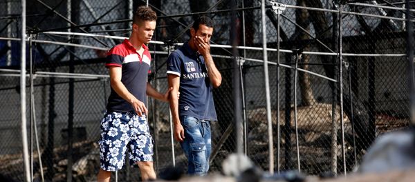 A migrant (R) reacts as he walks next to the remains of burned tents at the Moria migrant camp, after a fire that ripped through tents and destroyed containers during violence among residents, on the island of Lesbos, Greece, September 20, 2016. - Sputnik International