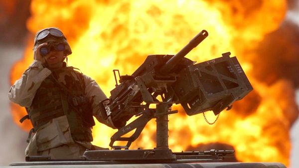 A US soldier looks through a pair of binoculars as a fire in the Rumeila oil field burns in the background in southern of Iraq, Sunday, March 30, 2003. - Sputnik International