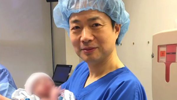 Dr. John Zhang of the Hope Fertility Center in New York holding the first 'three person baby' born using the new method - Sputnik International