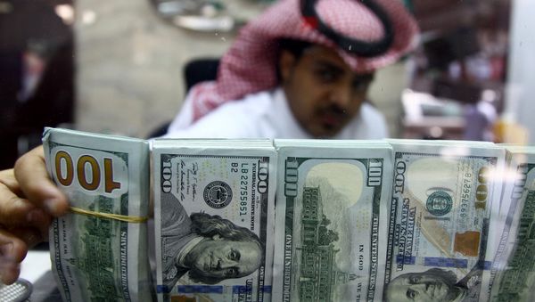 A Saudi money changer, pictured through a glass, arranges U.S banknotes at a currency exchange shop in Riyadh, Saudi Arabia September 29, 2016 A Saudi money changer, pictured through a glass, arranges U.S banknotes at a currency exchange shop in Riyadh, Saudi Arabia September 29, 2016 - Sputnik International
