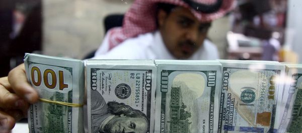 A Saudi money changer, pictured through a glass, arranges U.S banknotes at a currency exchange shop in Riyadh, Saudi Arabia September 29, 2016 - Sputnik International
