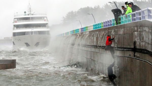 South Korean coast guards try to rescue crew members of a stranded passenger ship in the aftermath of typhoon Chaba in the southern city of Yeosu - Sputnik International
