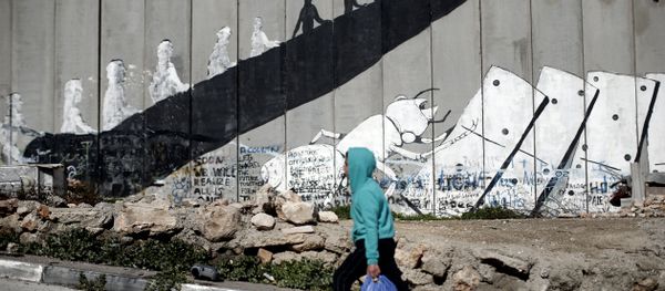 A Palestinian boy walks past graffiti painted on Israel's controversial separation barrier in the Aida refugee camp situated inside the West Bank town of Bethlehem, on February 12, 2016. A Palestinian boy walks past graffiti painted on Israel's controversial separation barrier in the Aida refugee camp situated inside the West Bank town of Bethlehem, on February 12, 2016. - Sputnik International