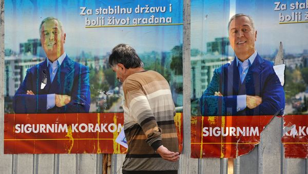 A man walks by election posters of Montenegrin Prime Minister Milo Djukanovic in Podgorica on October 14, 2016 - Sputnik International
