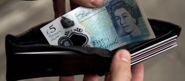 In this posed photograph a person is pictured holding a wallet containing a £5 (five pound) note in London on October 7, 2016. - Sputnik International