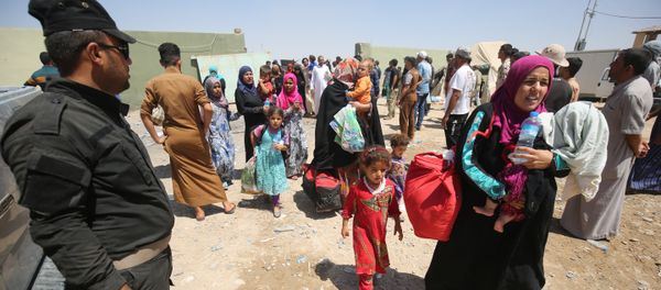 Iraqi security keep watch as civilians arrive on July 27, 2016 at a camp for displaced people in the district of Hajaj after fleeing the towns of al-Shirqat and Qayyarah, south of the city of Mosul, during reported fighting between Iraqi security forces and jihadists from the Islamic State (IS) grou - Sputnik International