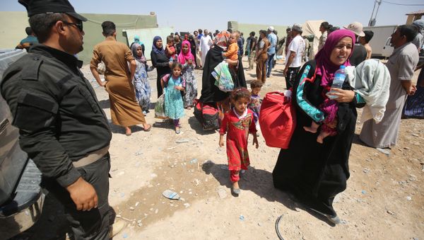 Iraqi security keep watch as civilians arrive on July 27, 2016 at a camp for displaced people in the district of Hajaj after fleeing the towns of al-Shirqat and Qayyarah, south of the city of Mosul, during reported fighting between Iraqi security forces and jihadists from the Islamic State (IS) grou - Sputnik International