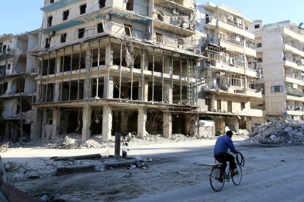 A man rides a bicycle near damaged buildings in the rebel held besieged al-Sukkari neighbourhood of Aleppo, Syria. (File) - Sputnik International