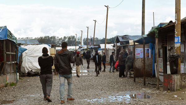 Migrants walks through the Jungle migrant camp in Calais, northern France, on October 22, 2016 - Sputnik International